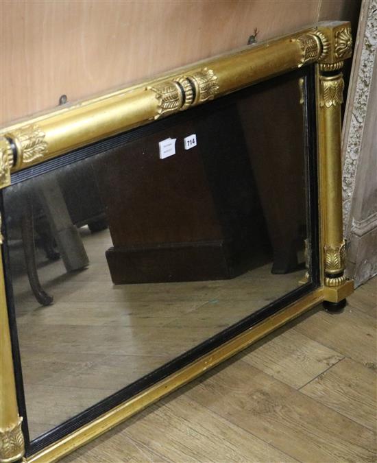 A William IV giltwood and ebonised overmantel mirror, with reeded slip flanked by foliate capped columns W.110cm